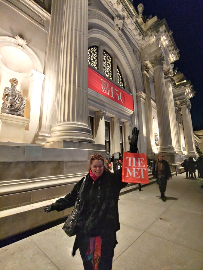 Lynne at the Wicked theater, holding her tickets, beaming